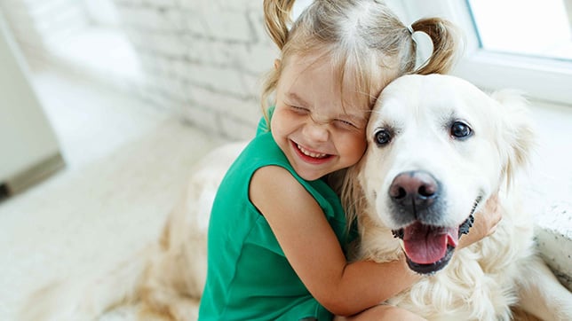 a little girl hugging a white dog