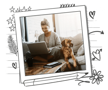 A woman is working at home whilst her dogs sits on the sofa next to her