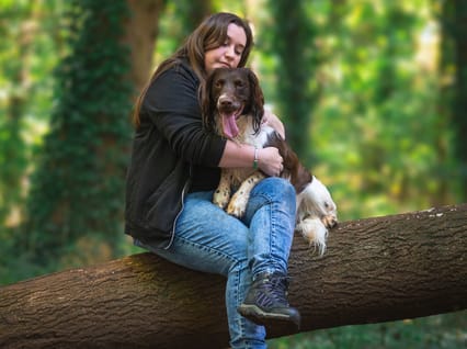 a spaniel sitting with their owner on a fallen tree 