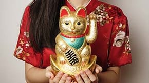 A woman holding a Maneki Neko (beckoning cat)