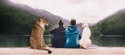A couple sit on a lakeside dock with their dog, and Iion