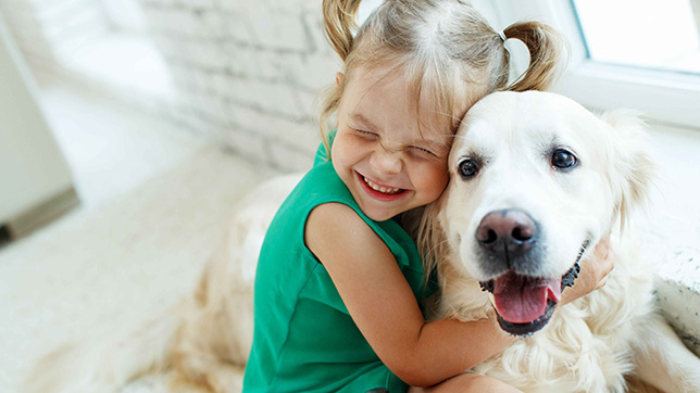 a little girl hugging a white dog